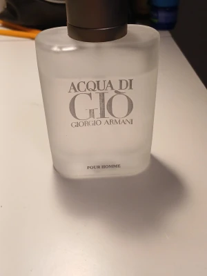 Acqua di Giò Pour Homme parfym - Acqua di Giò Pour Homme från Giorgio Armani är en klassisk herrparfym i en frostad, rektangulär glasflaska med silverfärgad kork. Flaskan har en stilren design med tydlig logotyp på framsidan. Perfekt för dig som gillar fräscha och maskulina dofter.
