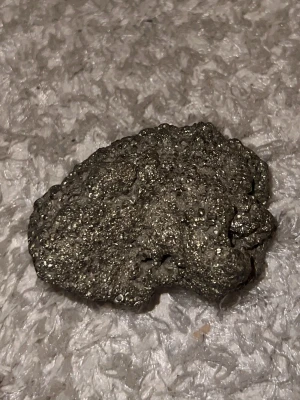 Glittrande pyritsten mineral - Säljer en rå, glittrande pyritsten med metallisk yta och oregelbunden form. Stenen har en skimrande guldaktig färg och är perfekt för dig som samlar mineraler eller gillar unika dekorationer. Pyrit är även känd som 'fool's gold' och är riktigt snygg i hyllan.