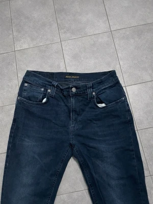 Nudie jeans - Mörkblå nudie jeans för män. Modellen är Thin finn, väldigt bekväma och skönt material. Storlek: Waist 32 / Lenght 34. Skick: Nyskick, inga skador/slitage. Hör av dig vid intresse/frågor. PRIS KAN DISKUTERAS!
