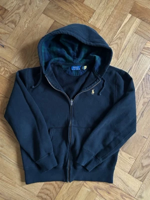  Polo Ralph Lauren Hoodie - Unik hoodie från Polo Ralph Lauren. Har huva med rutigt foder, fickor framtill och den ikoniska broderade loggan i gult på bröstet.