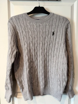 Grå kabelstickad tröja Polo Ralph Lauren - Kabelstickad Ralph Lauren tröja i fint skick. Klassisk och tidlös modell. Väldigt skön och passar till allt.  Storlek: S (Small) Skick: Väldigt Bra Pris: kan diskuteras  Om ni skulle vilja se mer bilder på tröja hör av er:)