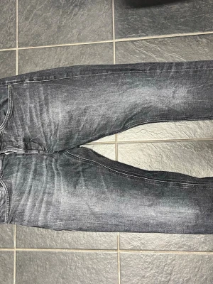 Svarta Dondup jeans - Säljer ett par grå/svarta jeans med tvättade detaljer. Jeansen har klassisk femficksmodell och raka ben. Perfekta för dig som gillar en avslappnad och trendig stil. Materialet är denim med skön stretch.                 Storlek: 33