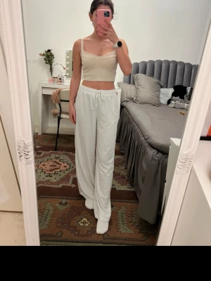 Vita vida loungewear-byxor - Säljer ett par superbekväma, vita loungewear-byxor med dragsko i midjan och breda ben. Perfekta för chill dagar hemma. Materialet ser mjukt och luftigt ut, vilket gör dem sköna att bära hela dagen.