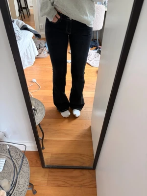 Svarta bootcut jeans med kontrastsömmar - Säljer ett par svarta bootcut jeans med vita kontrastsömmar och låg midja. 