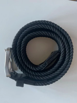 Svart flätat bälte från Jack & Jones - Snyggt svart flätat bälte från Jack & Jones med klassiskt silverfärgat spänne. Bältet har en stilren design och passar perfekt till jeans eller chinos. Gjort i skinn och syntetmaterial för både hållbarhet och stil.