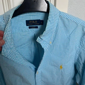 Blåvit rutig skjorta - Polo Ralph Lauren - Rutig skjorta från Ralph Lauren i blått och vitt. Perfekt för varma sommardagar! Storlek: L, slim fit. Skick:9/10. Kontakta oss för fler bilder eller info!🤗