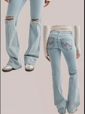 Ljusblå bootcut jeans med slitningar - Säljer ett par ljusblå bootcut jeans med slitningar på knäna och broderade detaljer på bakfickorna. Jeansen har låg midja och klassisk femficksdesign. Perfekta för en avslappnad och trendig look.