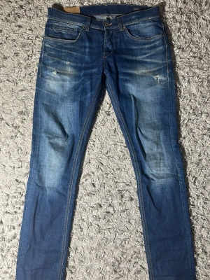 Blå slim fit dondup jeans med schyssta slitningar - Snygga blå slim fit jeans med lätt slitna detaljer och tvättad look. Jeansen har klassisk femficksdesign och normal midja. Perfekta för en avslappnad och trendig stil. Längd: 103cm midja: 41cm