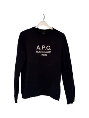 Svart sweatshirt från A.P.C. - Klassisk svart sweatshirt från A.P.C. med vit text 'A.P.C. RUE MADAME PARIS' på bröstet. Tröjan har rund halsringning och långa ärmar. Perfekt för en clean och stilren look. Köpt från bestsecret. Storlek S men är ganska tajt, så XS funkar också!