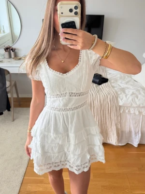 Vit miniklänning med spetsdetaljer - Superfin vit miniklänning med volanger och spetsdetaljer. Även perfekt som studentklänning! Aldrig använd med lapp kvar, nyspris: 799kr 🥰