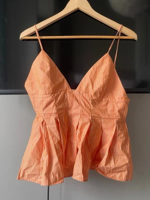 Zara randig orange linnetopp - Snygg orange linnetopp med vita ränder och smala axelband från Zara. Toppen har v-ringad hals och lätt utsvängd passform med veckade detaljer. Perfekt färg för sommaren. Några av sömmarna har lossnat lite❣️
