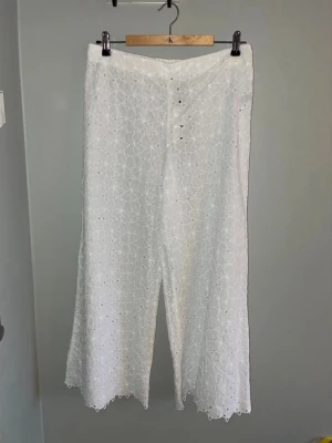 Vita broderade byxor Kappahl - Snygga vita byxor från Kappahl i storlek M. Byxorna har broderat blommönster, raka ben och elastisk midja. Perfekta för en chill och stilren look. Materialet är luftigt och lätt, vilket gör dem grymt sköna under varma dagar.