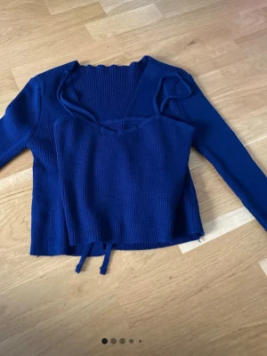 Mörkblå stickad topp och cardigan - Säljer ett set med mörkblå stickad topp med smala axelband och matchande långärmad cardigan. Båda plaggen har ribbstickad struktur och är i mjukt material. Perfekt att bära tillsammans eller var för sig för en trendig lager-på-lager-look.