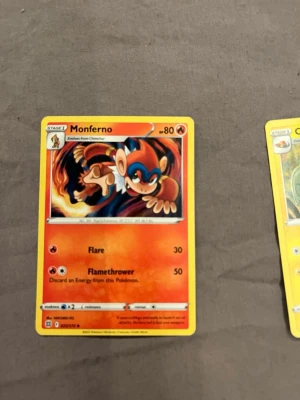 Pokémonkort Monferno - Säljer ett Pokémonkort med Monferno-motiv. Kortet har en färgstark design i orange, rött och blått med Monferno i en actionpose och eld i bakgrunden. Text och symboler i svart och vitt. Perfekt för samlare eller Pokémonfans.