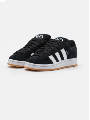 Adidas Campus svart/vit sneakers - Svarta Adidas Campus sneakers i mocka med klassiska vita ränder på sidorna och vit sula med gummidetalj. Tjocka svarta skosnören och Adidas-logga på plösen. Perfekt för en streetwear-look.