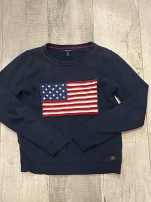 Marinblå Gant stickad Amerika tröja - Säljer en riktigt snygg mörkblå/marinblå stickad tröja från gant med ett amerikansk flagga i mitten. Väldigt bra skick, storleken står S men passar bättre på XS. Kontakta om intresserad eller frågor!