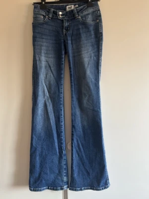 Blå bootcut jeans från 157 och low rise  - Snygga blå bootcut jeans från 157 med klassisk femficksdesign och broderade detaljer på bakfickorna. Jeansen har normalhög midja och är tillverkade i denim med lätt tvättad look. Perfekta för dig som gillar en avslappnad men trendig stil.