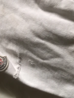 Vit kofta från Moncler - Snygg vit dunväst från Moncler med quiltat mönster och dragkedja framtill. Västen har två fickor med dragkedja och klassisk Moncler-logga på sidan. Perfekt för lager-på-lager och en clean look. Den är lite trasig på armen och dragkedjan e lite sönder men den funkar att knäppa upp inte hela vägen bara därför säljer jag denna för en mycket bra pris 