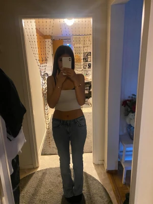 Ljusblå bootcut jeans - Säljer ett par ljusblå bootcut jeans med klassisk femficksdesign och normal midja. Jeansen har en snygg passform som framhäver benen och är tillverkade i denim. Perfekta för dig som gillar en avslappnad och trendig stil.