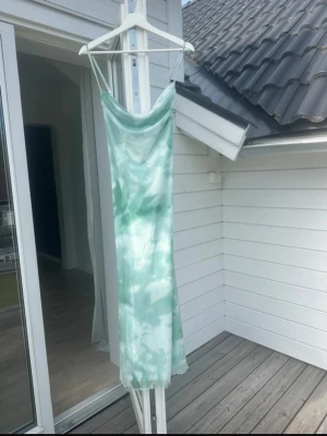 Grön och vit långklänning med tunna band - Aldrig använd. Säljer en långklänning med tunna axelband i ett snyggt grönvitt. Perfekt för varma dagar och somriga tillfällen.