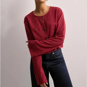 Röd kofta/cardigan med knappar - En röd cardigan från Nelly med stora knappar framtill. Koftan är croppad och har långa ärmar, använd en gång. Storlek xxs men passar även xs och s. Tröjan är mindre mörkröd i verkligheten