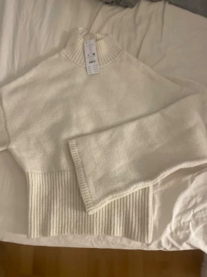 Vit stickad tröja  - Snygg vit stickad polotröja från gina tricot med bred ribbad mudd i midjan och vid halsen. Tröjan har långa ärmar och en hög krage som ger en trendig look. Perfekt att matcha med jeans eller kjol för en stilren outfit. helt ny 