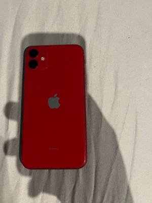 Röd iPhone 11  - Säljer en snygg röd iPhone 11 från Apple. Telefonen har en stilren design med glasbaksida. Batterihälsan på telefonen är 80%