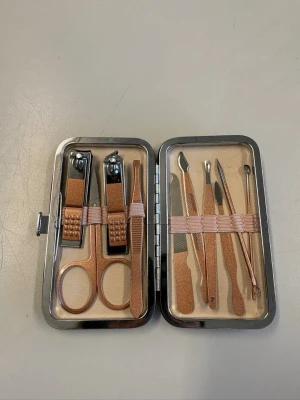 Nagelvårdset i roséguld - Ett komplett nagelvårdset i snygg roséguld-färg med nagelklippare, sax, pincett, nagelfil och olika verktyg för nagel- och nagelbandsvård. Allt ligger i ett smidigt fodral med metallram, perfekt att ha med sig.