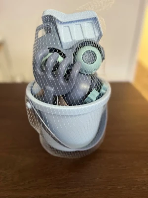 Blått sandlådeleksaksset i plast - Säljer ett sandlådeleksaksset i blå och grå plast med hink, spade, lastbil och sandformar. Perfekt för lek i sandlådan eller på stranden. Alla delar har mjuka pastellfärger och är lätta att bära med sig tack vare hinkens handtag. 100% giftfritt 