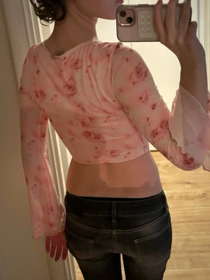 Blommig tröja🩷 Märke: shein  - Säljer en väldigt fin blommig tröja❤️ Kort i magen men långa armar som sitter löst, längst ut på armarna är det vågigt. Där fram finns det en rosett (man knyter själv) och sömmar som gör att det ser ”skrynkligt” ut men på ett fint sätt. Armarna är lite genomskinliga. Där bak är det blommigt men inga andra sömmar. Det är en fin ljus rosa färg på tröjan med mörkare blommor på, ser ut som rosor. Fin till sommaren! Tror det är xs men kan säkert användas som s. 