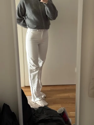 Vita raka jeans med hög midja - Säljer ett par vita jeans med hög midja och raka ben. Jeansen har klassiska fickor fram och bak samt dragkedja och knappstängning. Materialet är denim med lite stretch 