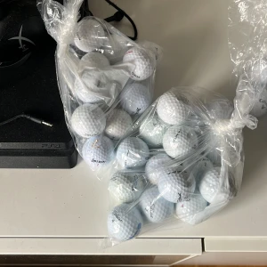 Två påsar med golfbollar - Säljer två plastpåsar fyllda med vita golfbollar av olika märken. Perfekt för dig som vill fylla på golfutrustningen med extra bollar. Bollarna har klassisk rund form och dimpled yta för bättre flyg.