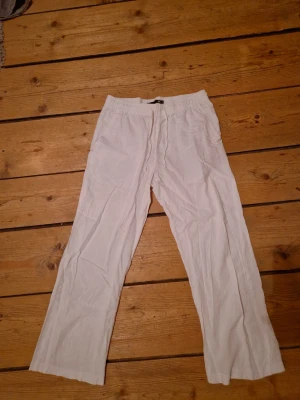 Vita linnebyxor från 157, storlek S - Säljer ett par vita linnebyxor från Lager i storlek S. Byxorna har resår och dragsko i midjan samt raka ben. Perfekta för en avslappnad och stilren look. Tillverkade i lätt och luftigt linnematerial.