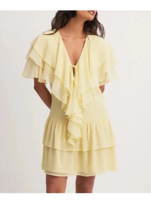 Ljusgul volangklänning med knyt - Superfin ljusgul klänning med volanger och v-ringning. Klänningen har kort längd, knyt framtill och flera lager volanger både upptill och nertill. Perfekt för varma dagar och ger en romantisk vibe. Tillverkad i ett lätt och luftigt material.