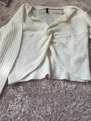 Vit stickad tröja med knut framtill - Säljer en vit stickad tröja från H&M med snygg knut framtill. Tröjan har lång ärm, lös passform och är tillverkad i ett mjukt, grovstickat material. Perfekt för sommaren och enkel att styla till olika outfits.