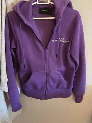 Lila hoodie från Peak Performance - Lila hoodie från Peak Performance med dragkedja, huva med dragsko och fickor framtill. Säljer då jag inte använder den!🤍