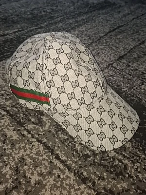 keps med GG-mönster - Snygg keps i beige med klassiskt GG-monogram över hela kepsen. Har en grön och röd rand på sidan och justerbart spänne bak med. Tillverkad i canvasmaterial som ger en exklusiv känsla.