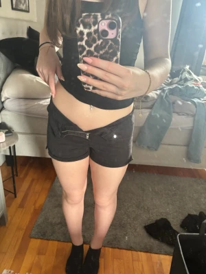 Svarta lågmidjade shorts med dragkedja - Säljer ett par svarta lågmidjade shorts med dragkedja och knapp framtill. Shortsen har fickor både fram och bak samt bälteshällor. Även liten slits på båda sidorna❤️