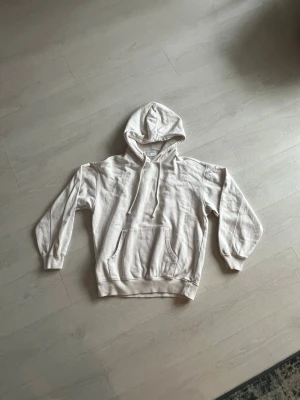 Vit hoodie från Vailent - Snygg beige hoodie från Vailent i storlek S. Hoodien har huva med dragsko, magficka och ribbade muddar vid ärmslut och nederkant. Mjuk insida i fleece för extra komfort. Perfekt för en avslappnad och stilren look.