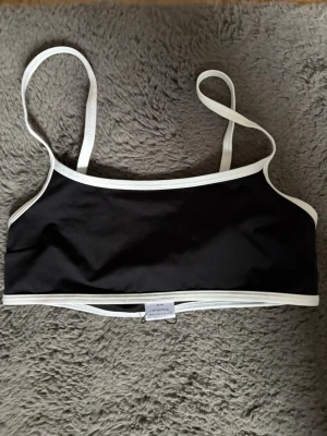 Svart bikini från lager 157 - Stilren svart bikiniöverdel med tunna axelband och kontrasterande vita kanter. Enkel och sportig design som passar perfekt till stranden eller poolen. Tillverkad i ett stretchigt material för bekväm passform. Aldrig använt!💕❣️