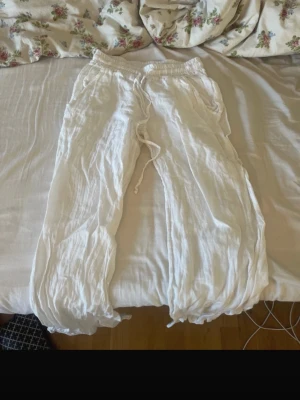 Vita linnebyxor från Chelsea Girls - Säljer ett par vita linnebyxor från Chelsea Girls i storlek S. Byxorna har resår i midjan och dragsko för skön passform. Tillverkade i 100% linne vilket gör dem luftiga och perfekta för varma dagar. Vida ben och avslappnad stil.