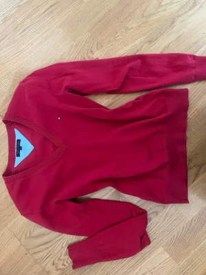 Röd tröja från Tommy Hilfiger - Snygg röd v-ringad tröja från Tommy Hilfiger.  Tröjan är i storlek S