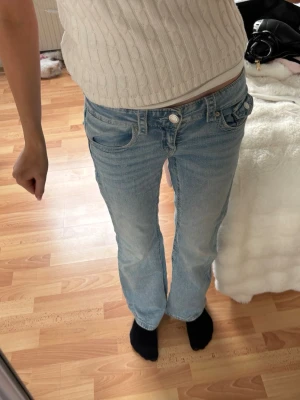 Ljusblå bootcut jeans med fickdetaljer - Säljer ett par ljusblå bootcut jeans med snygga fickdetaljer bak och klassisk femficksmodell. Jeansen har normal midja och är i mjukt denimtyg. Perfekta till en avslappnad look och passar till det mesta.