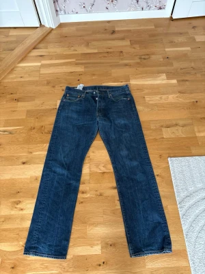 Mörkblå raka jeans från Levi's - Säljer ett par klassiska mörkblå jeans från Levi's med rak passform och fem fickor. Jeansen har snygga kontrastsömmar och är tillverkade i slitstark denim. Perfekt för dig som gillar en tidlös och enkel stil.