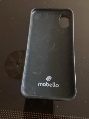 Svart marmormönstrat mobilskal Mobello - Snyggt svart mobilskal från Mobello med marmormönster och diskret logga. Skalets material är tålig plast och det har en öppning för kameran. Perfekt för dig som vill ha ett stilrent och trendigt skydd till din mobil.