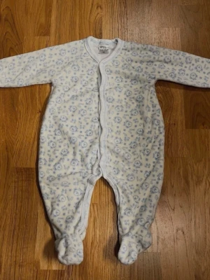 Vit / ljusblå sparkdräkt från S & S Silvi Style - Storlek 68 - Fin och mysig sparkdräkt i vit och ljusblå med gulligt nallemönster. Perfekt för både vardag, lek och sovstunder! Långärmad modell. Med fötter - håller små fötter varma! Knäppning framtill med knappar - lätt att ta av/på. Varumärke: S & S Silvi Style. Storlek: 68 (4–6 månader) Material: 80% Bomull och 20% Polyester. Säljs i begagnat skick. Kika gärna in på mina andra annonser, jag säljer flera barnplagg!