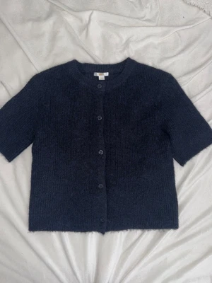 Mörkblå kortärmad kofta Gina Tricot - Mysig mörkblå stickad kofta från Gina Tricot med korta ärmar och rund halsringning. Mycket bra skick. Storlek 158/164