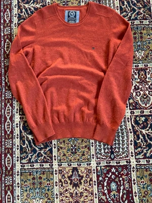 Rostfärgad stickad tröja State of Art - Snygg rostfärgad stickad tröja från State of Art med rund halsringning och diskret logga på bröstet. Tröjan har regular fit och ribbstickade muddar vid ärmslut och nederkant. Perfekt för lager-på-lager och enkel att matcha.