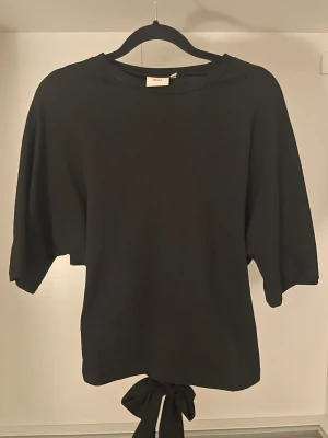 Tröja  - En svart tröja som man knyter i bak från Nelly storlek S 