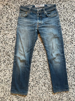 Jacob Cohën Jeans - Snygga blå jeans från det italienska märket Jacob Cohën. Jeansen har klassisk femficksmodell, metallknappar och ljusa slitningar framtill för en exklusiv look. Tillverkade i japanskt denimtyg. Passar storlek XS/S eller ca 160-170 cm lång. Pris kan diskuteras vid snabb affär. 